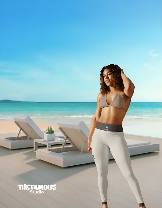 Woman with a sand and turquoise leggings outfit standing on a beach with lounge chairs and clear sky.